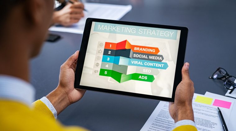 Digital marketing strategy Close up of young man using digital tablet to study marketing strategy. African businessman studying business planning. Rear view of student holding tablet in hands and analyze business material on screen.