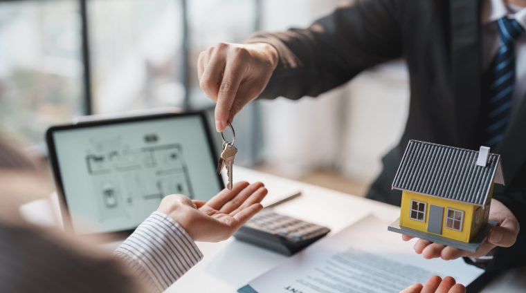 Real estate agent gives the couple the keys to the house after t Real estate agent gives the couple the keys to the house after they sign the real estate sale contract. House and real estate trading concept.